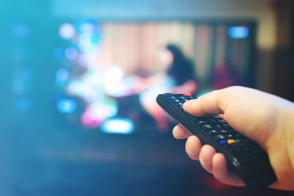 person pointing television remote to tv
